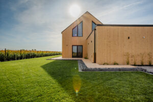 Usługi ogrodnicze Krobia - ścieżka przy domu otoczona zielonym, zadbanym trawnikiem, nowoczesna drewniana zabudowa.