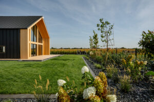 Usługi ogrodnicze Krobia - rabaty z różnorodnymi roślinami, kwitnące krzewy, trawy ozdobne przy nowoczesnym domu