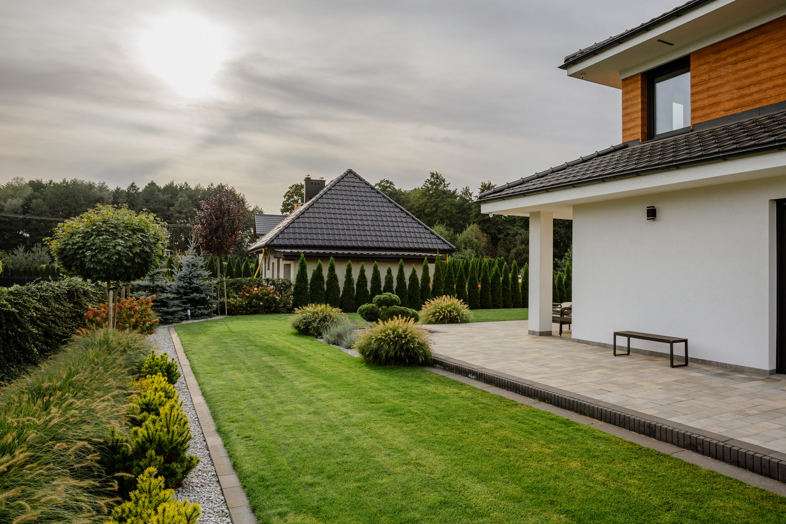 Zadbany ogród z pięknym trawnikiem, przeciętymi krzewami i nowoczesną zabudową - usługi ogrodnicze Grębocin